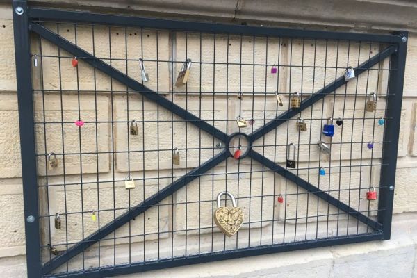 INSOLITE. Il installe une grille sur sa façade, des gens y accrochent de nombreux cadenas