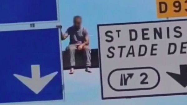 Un homme inconscient grimpe sur un panneau à plusieurs mètres au-dessus de l'autoroute, le trafic interrompu