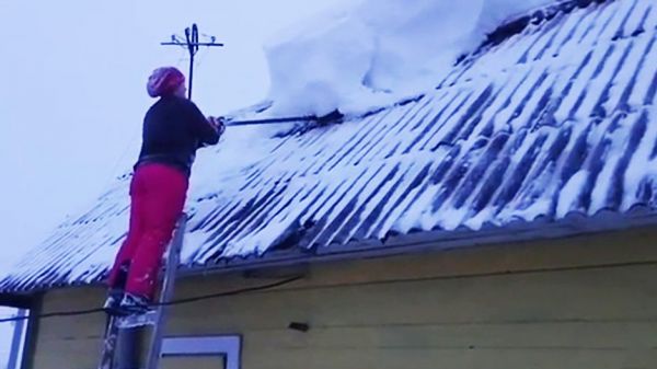 Une femme entrain de déneiger son toit