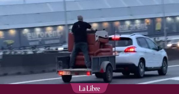 Un homme se tient debout sur une remorque sur l'autoroute en région liégeoise